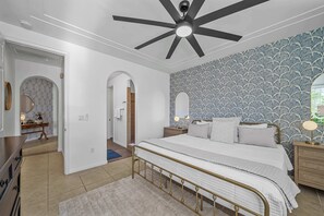 A bedroom with a bed, a ceiling fan, a nightstand, and a dresser. - Casa Veranda | Puerta Azul Pool Retreat (La Quinta)