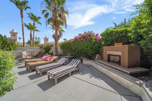 A patio with lounge chairs, a fire pit, and a stone wall with greenery. - Casa Veranda | Puerta Azul Pool Retreat (La Quinta)