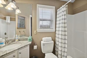 A bathroom with a sink, mirror, toilet, and shower curtain. - Serene 2-bedroom cottage with fireplace in charming Gatlinburg (Gatlinburg)