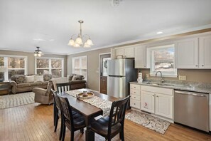 A spacious kitchen with a dining area, white cabinetry, stainless steel appliances, and a ceiling fan. - Serene 2-bedroom cottage with fireplace in charming Gatlinburg (Gatlinburg)