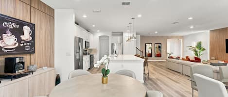 A modern kitchen with white cabinets, stainless steel appliances, and a coffee machine.