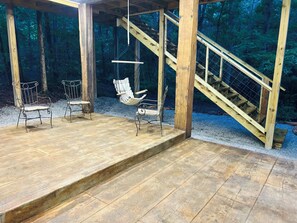 Eine Holzterrasse mit zwei Metallstühlen und einer Hängematte.