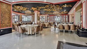 A spacious dining area with round tables, chairs, and a decorative ceiling.
