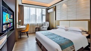 A hotel room with a bed, a TV, a desk, a chair, and a window with curtains.