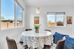 A dining area with a round table, chairs, a potted plant, and artwork on the walls. - Sonoran Summer Stay | Near Downtown & UofA (Tucson)