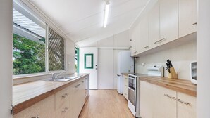 A modern kitchen with wooden cabinets, a stainless steel sink, and a built-in oven. - Ocean Soul Unit 1 (Burnett Heads)