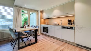 Eine moderne Küche mit Essbereich, ausgestattet mit Backofen, Geschirrspüler und Kaffeemaschine.