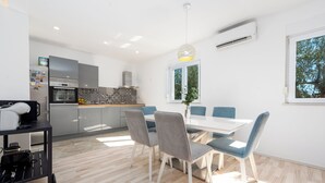 Une cuisine moderne avec un coin repas, une grande fenêtre et un luminaire au plafond.