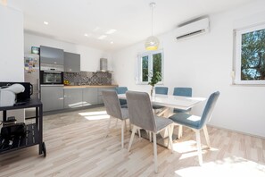 A modern kitchen with a dining area, a large window, and a ceiling light fixture. - Olive House Pool & Garden, Zemunik Donji, Croatia (Zemunik Donji)