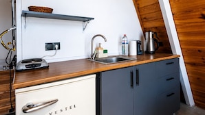 A kitchen with a wooden ceiling, a white wall, a sink, a coffee maker, and a VESTEL refrigerator.