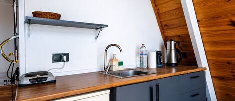 Une cuisine avec un plafond en bois, un mur blanc, un évier, une machine à café et un réfrigérateur VESTEL.