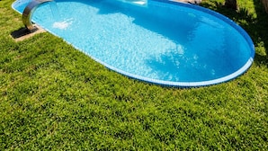 A modern house with a swimming pool, a wooden deck, and a hanging chair.