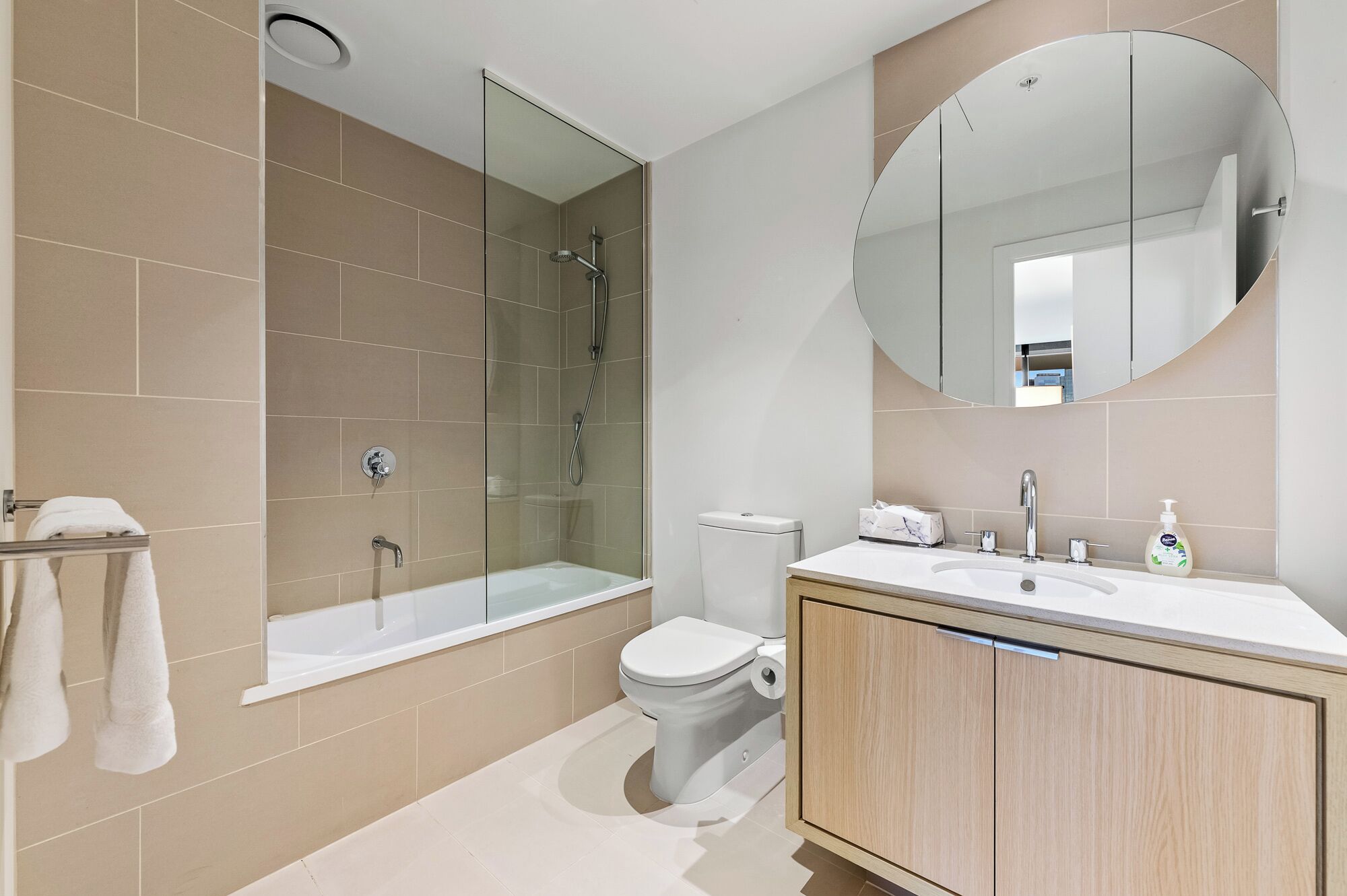 Een moderne badkamer met een douchecabine van glas, een toilet en een wastafel met spiegel.