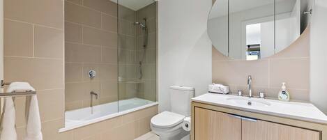 Een moderne badkamer met een douchecabine van glas, een toilet en een wastafel met spiegel.