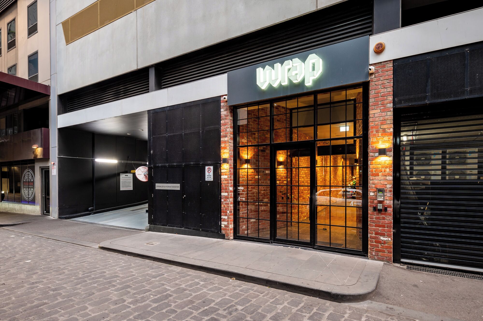 A building with a 'wrap' sign, a brick facade, and a closed black shutter door.