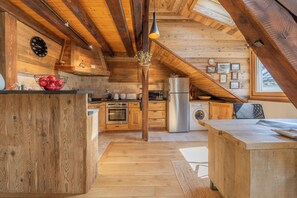 A rustic kitchen with wooden beams, a central island, and a hanging light fixture. - Cristal in the heart of Chamonix Mountain view for 6, Chamonix, France (Chamonix)