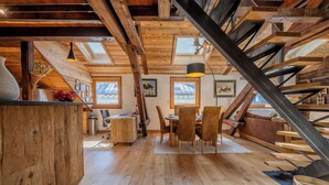 Et rustikt interiør med træbjælker, et spiseområde og en trappe.