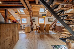 A rustic interior with wooden beams, a dining area, and a staircase. - Cristal in the heart of Chamonix Mountain view for 6, Chamonix, France (Chamonix)