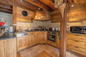 A kitchen with wooden cabinets, a dishwasher, an oven, and a microwave. - Cristal in the heart of Chamonix Mountain view for 6, Chamonix, France (Chamonix)