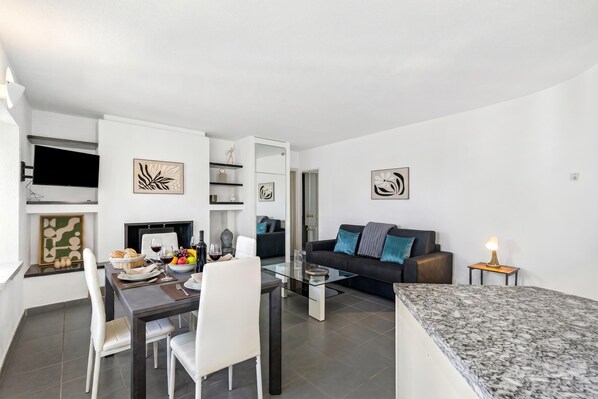 A modern living space with a dining area, a sofa, and a TV mounted on the wall.