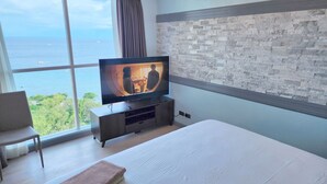 A hotel room with a large window, a television, a bed, and a seating area. - Huge Lux. 2 BR Condo (100 SQM)  2 pools - Beach, Sea-views, Gym, Tours available (Lapu-Lapu City)