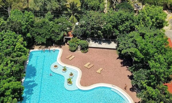 A resort with a large swimming pool, lush greenery, and a view of the ocean. - Huge Lux. 2 BR Condo (100 SQM)  2 pools - Beach, Sea-views, Gym, Tours available (Lapu-Lapu City)