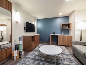 Ein modernes Wohnzimmer mit Flachbildfernseher, Holzschränken, einem runden Tisch und einer blauen Akzentwand.