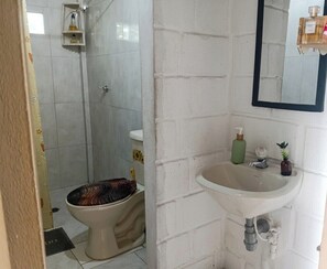 Un baño con inodoro, lavabo y zona de ducha.