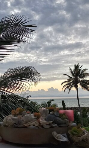 Vista de una playa con palmeras y un atardecer.