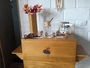 A wooden dresser with a decorative flower design, a coffee maker, a glass carafe, and a small wooden stand.