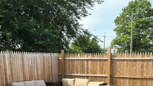 Un espacio al aire libre con sofá modular, una mesa de centro, una valla de madera y suelo de grava.