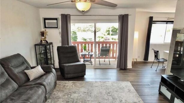 A living room with a sofa, a chair, a TV, and a balcony with a table and chairs. - Gorgeous 2-bedroom condo with AC in Long Beach two garages (Long Beach)