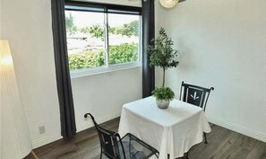 A dining area with a table, chairs, a potted plant, and a window with a view. - Gorgeous 2-bedroom condo with AC in Long Beach two garages (Long Beach)