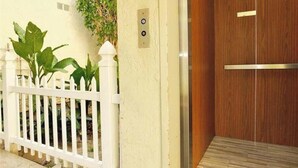 A white picket fence, a wooden door, and a wall-mounted intercom. - Gorgeous 2-bedroom condo with AC in Long Beach two garages (Long Beach)
