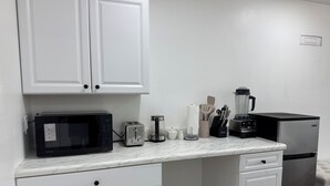 A kitchen with white cabinets, a microwave, toaster, coffee maker, blender, and refrigerator. - Studio Suite Near Ouachita River & Hot Springs (Malvern)