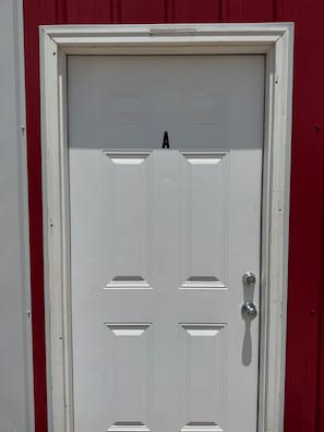 A white door with a letter 'A' above it, a keyhole on the right, and a red wall to the left.