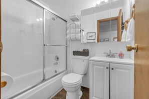 Une salle de bain moderne avec une douche à parois de verre, des toilettes blanches et un lavabo avec un miroir au-dessus.