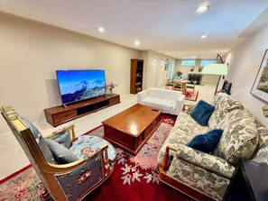 A living room with a television, sofa, coffee table, and a patterned rug. - hot tub villa with a sauna room (Surrey)