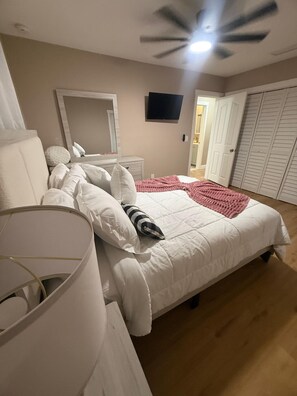 Ein Schlafzimmer mit Bett, Nachttisch, Spiegel, Fernseher und Kleiderschrank.