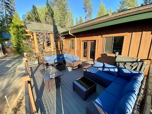 A wooden deck with outdoor furniture, a covered seating area, and a building with large windows.