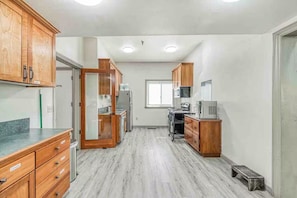 A kitchen with wooden cabinets, a refrigerator, a microwave, and a window.