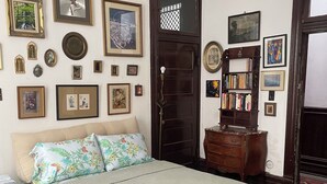 Een slaapkamer met een bed, een dressoir, een boekenplank en diverse ingelijste foto's aan de muren.