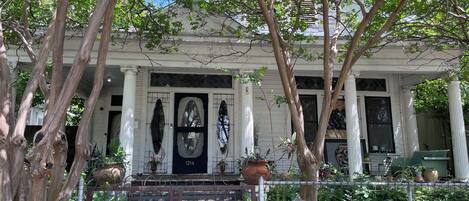 A white building with a black door, columns, and a covered porch.