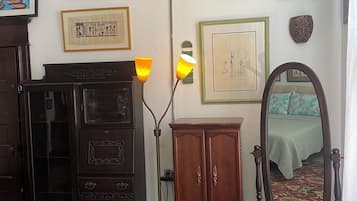 A room with a wooden cabinet, a mirror, and various framed artworks on the wall.