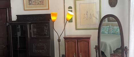 Una habitación con un armario de madera, un espejo y varias obras de arte enmarcadas en la pared.