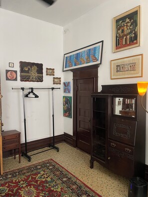 Ein Zimmer mit einem Holzkabinett, einer Hängelampe, einem gemusterten Teppich und verschiedenen gerahmten Kunstwerken an der Wand.
