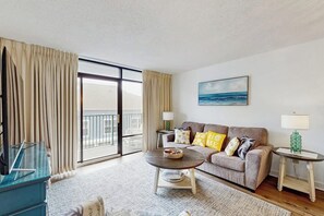 Una sala de estar con sofá, mesa de centro, televisor y balcón.