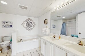 Une salle de bain avec une baignoire, un lavabo, des toilettes et un miroir.