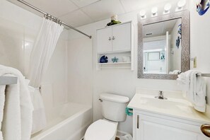 A bathroom with a shower, toilet, sink, and vanity.