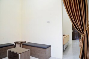 Habitació moderna amb un sofà, una taula petita i una banca. Hi ha una porta que condueix a una altra habitació.